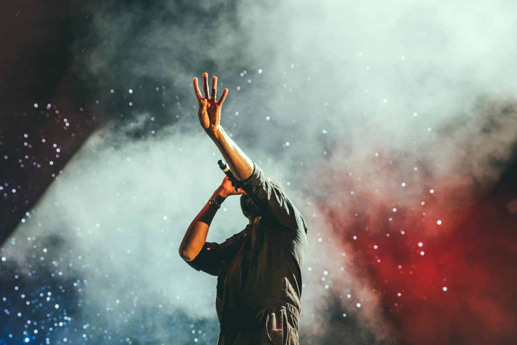 Performer raising a hand on a smoke-filled stage